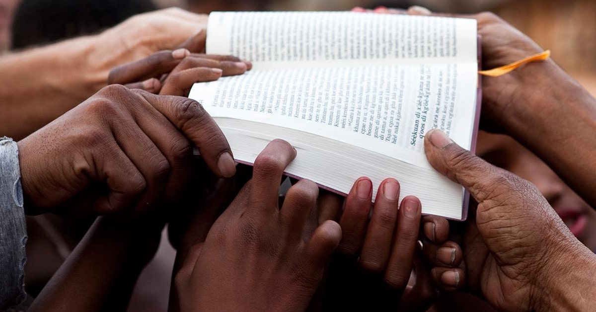 different races of hands on a bible